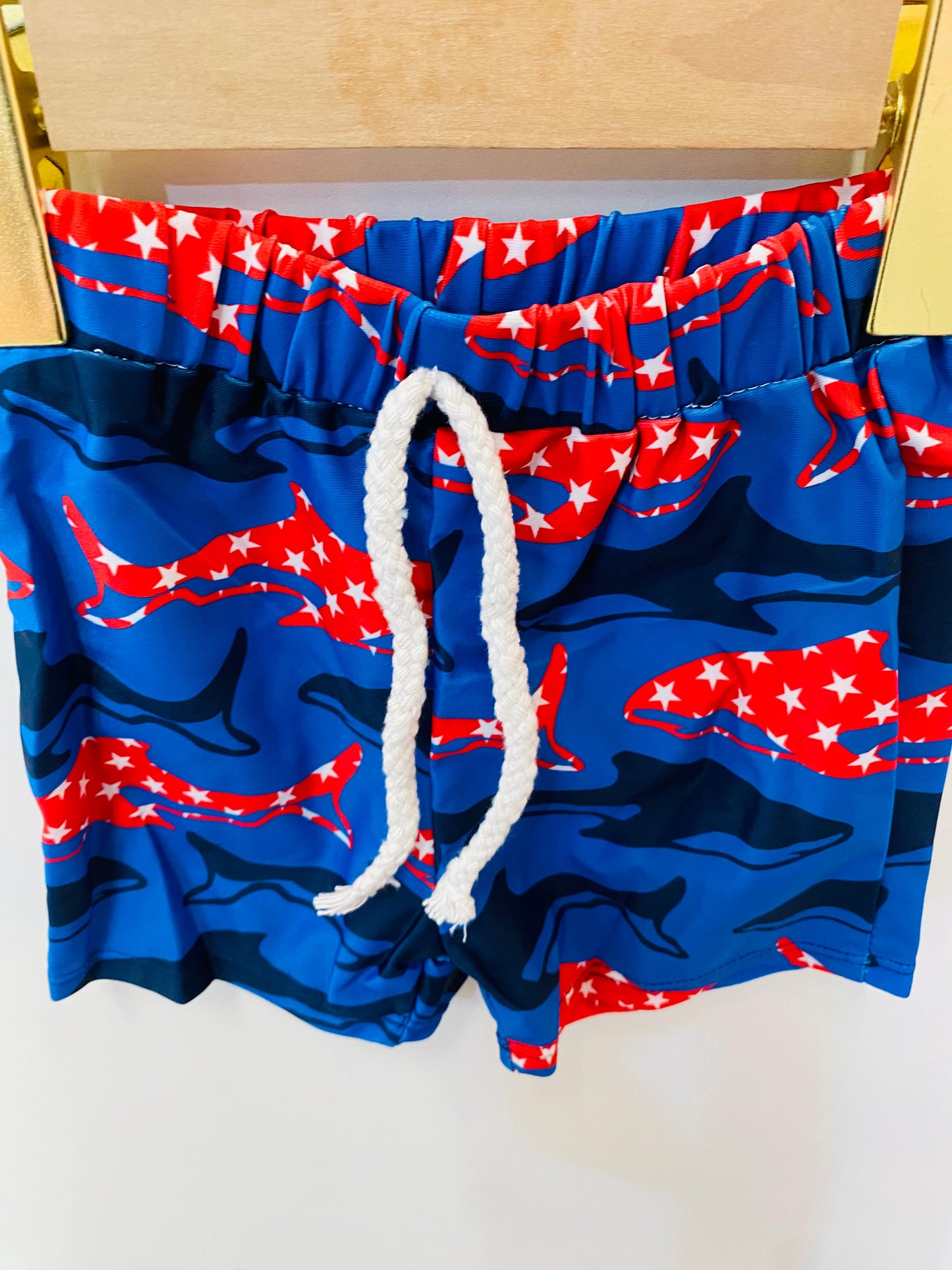 Blue swim shorts with red and white fish pattern on a white background