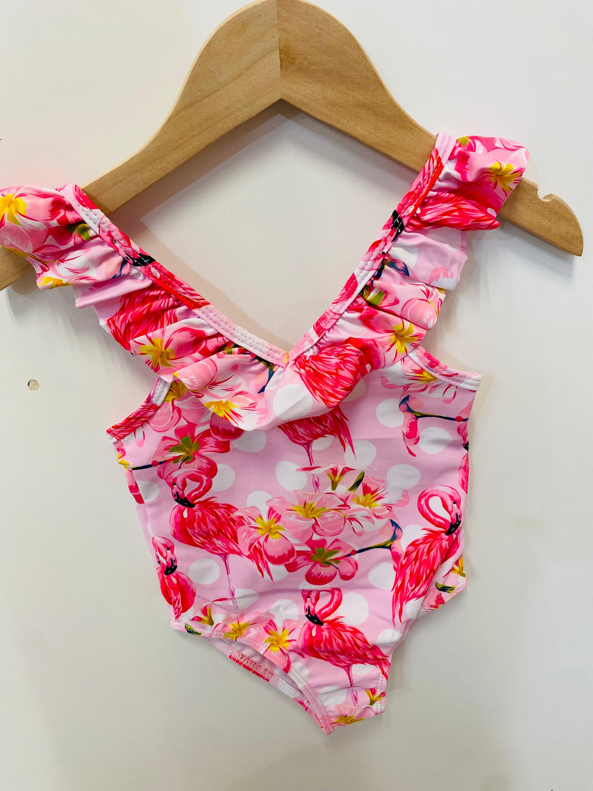 Pink floral swimsuit on a wooden hanger against a white background