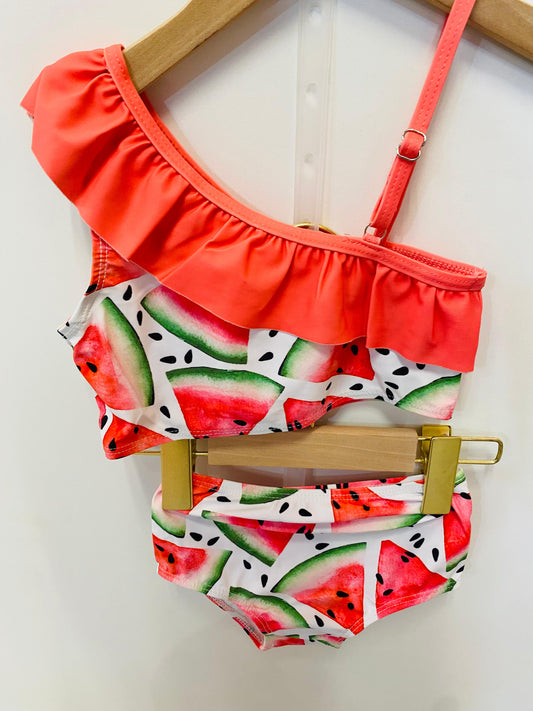 Two-piece swimsuit with watermelon pattern on a hanger against a white background