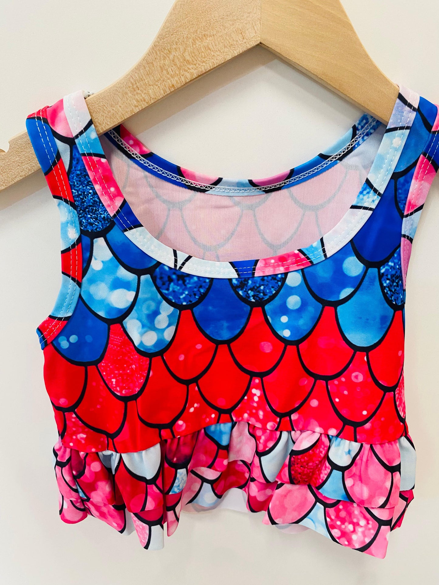 Colorful swimsuit with mermaid scale pattern on a wooden hanger