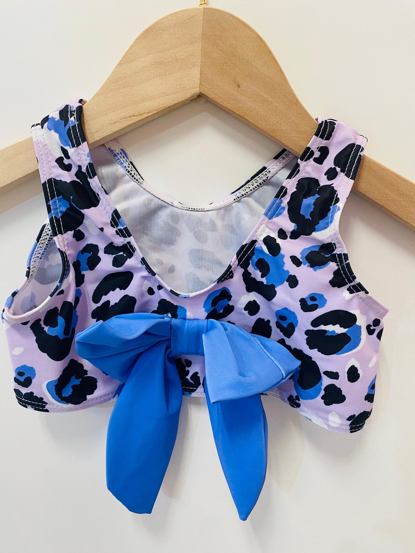 Children's swimsuit with leopard print and purple bow on a hanger